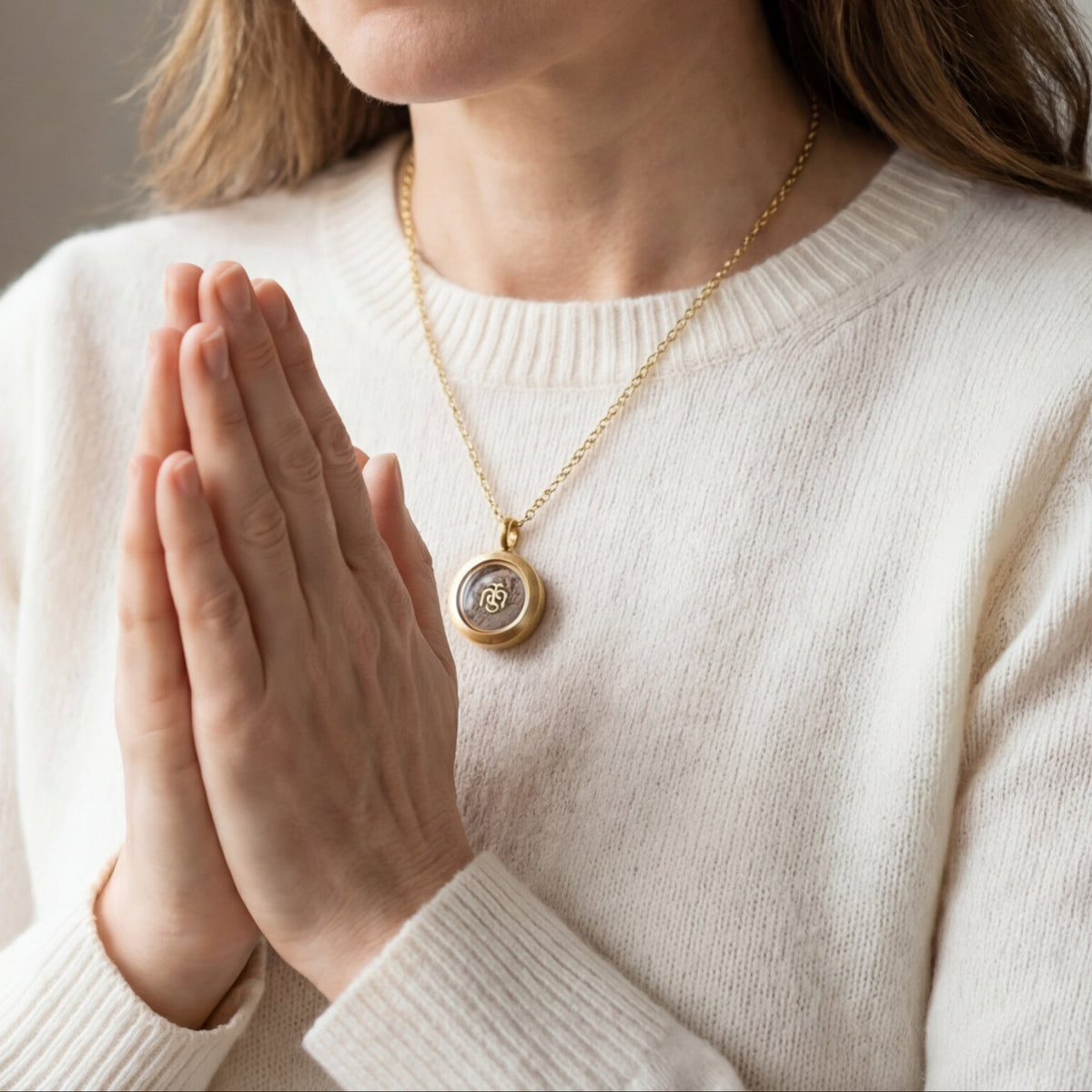 Gold Locket of Divine Promise worn on a chain, with hands folded in prayer