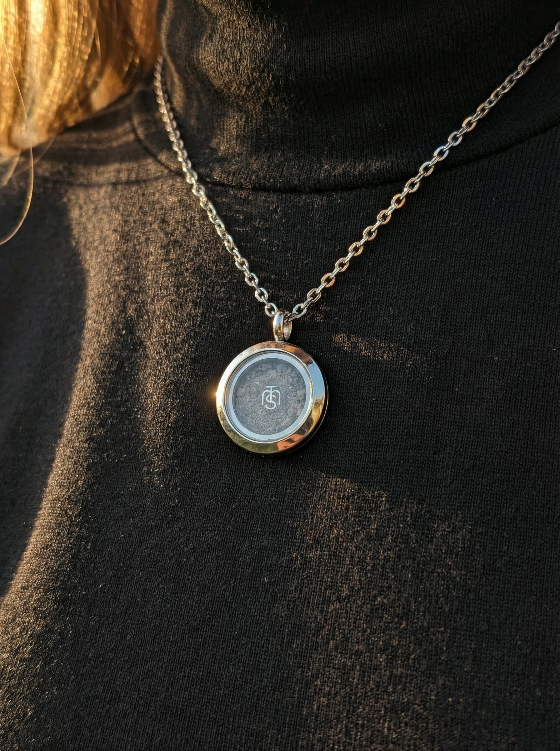 Silver Locket of Divine Promise worn on a chain over a black turtleneck