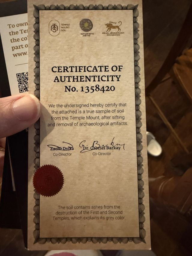 A customer holding a numbered Certificate of Authenticity signed by Zachi Dvira and Dr. Gabriel Barkay