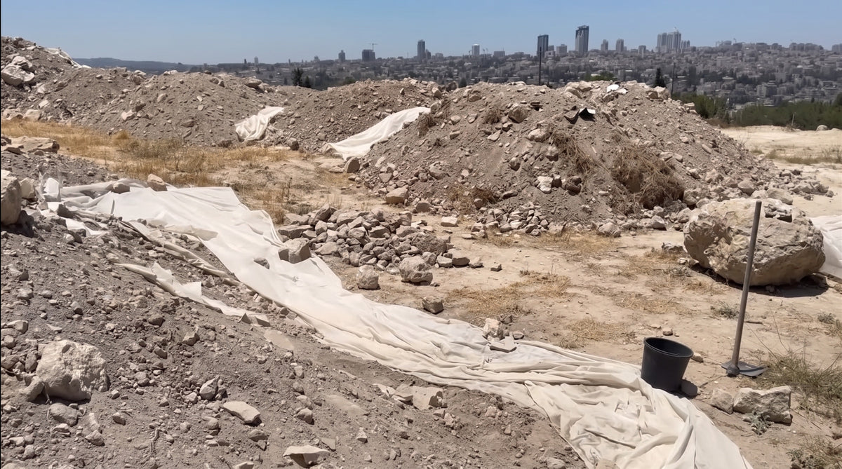 Soil piles under cover with the Jerusalem skyline behind